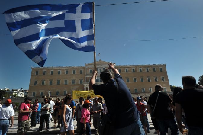 A protester holding a Greek flag gestures toward parliament in Athens on Wednesday, September 26. Greek trade unions called a 24-hour general strike to oppose new austerity measures. Police said some protesters threw Molotov cocktails in Syntagma Square, opposite the  parliament building. Police responded with tear gas. <a >See anti-austerity protests in Spain</a>.