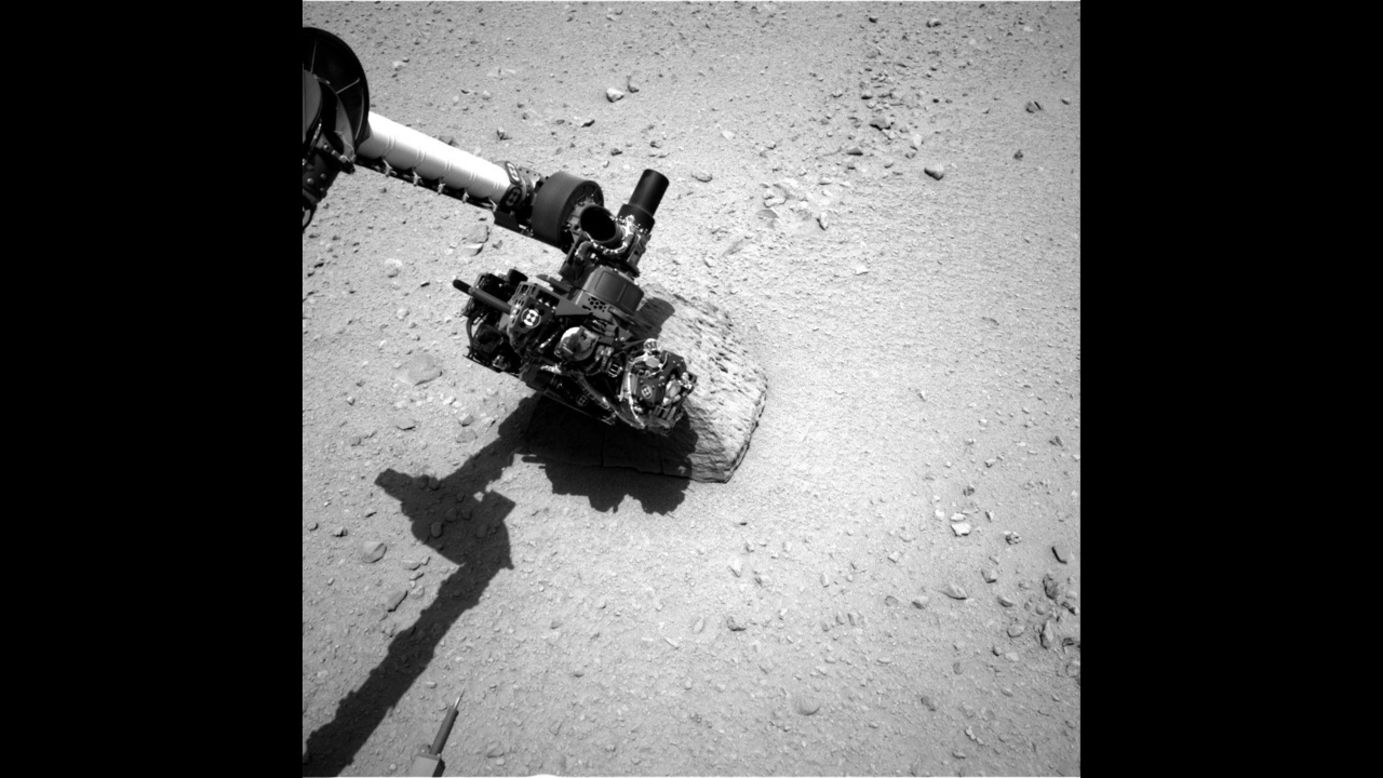 This image shows the robotic arm of NASA's Mars rover Curiosity with the first rock touched by an instrument on the arm. The photo was taken by the rover's right navigation camera.