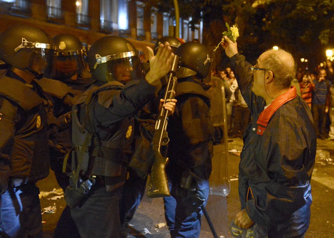 A man hands a flower to riot police during the protest against the government's handling of the economic crisis.