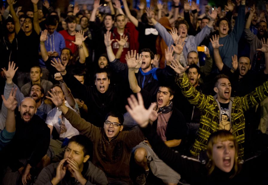 Demonstrators raise their hands during the protest against government spending cuts.