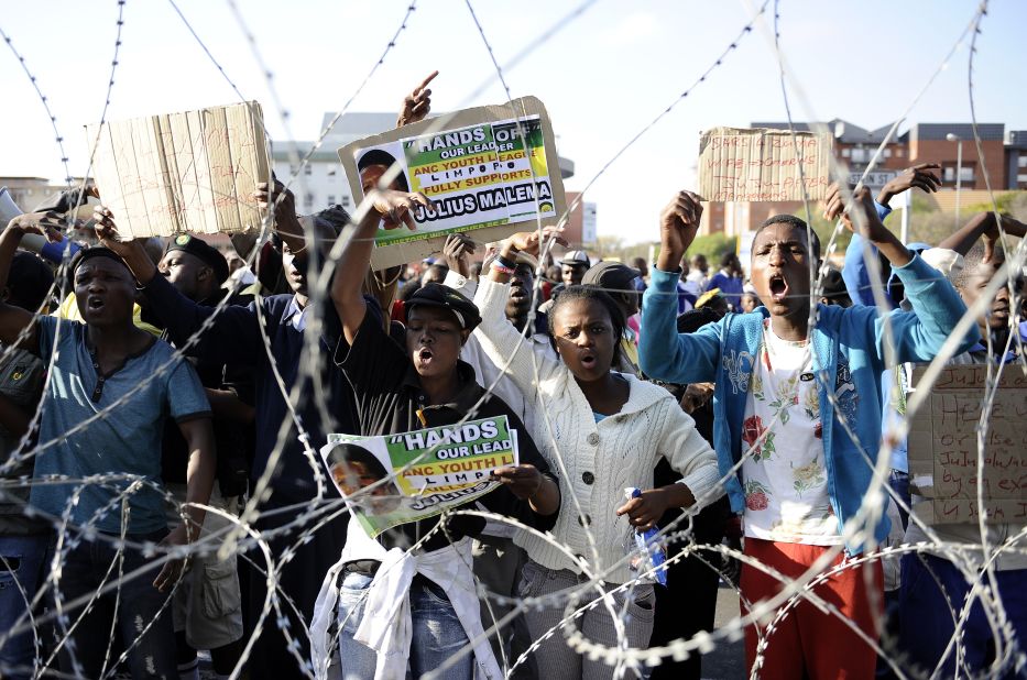 Demonstrators gather behind a razor wire outside the courthouse on September 26, singing songs in Malema's support. Some held an overnight vigil at a local hall amid heavy security presence that included riot police.