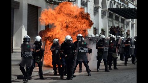 A fire bomb explodes behind a riot police squad on Wednesday.