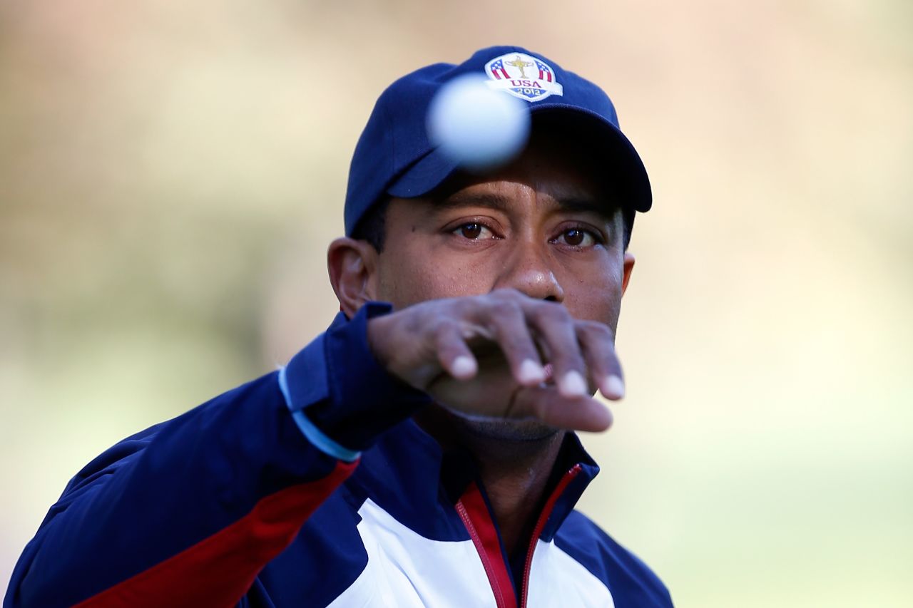 Team U.S.'s Tiger Woods reaches for a golf ball on the practice ground on Thursday.