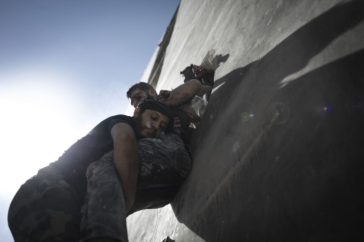 Men carry the covered body of a child killed in an attack by Syrian government forces in Aleppo on Friday, Spetember 28.