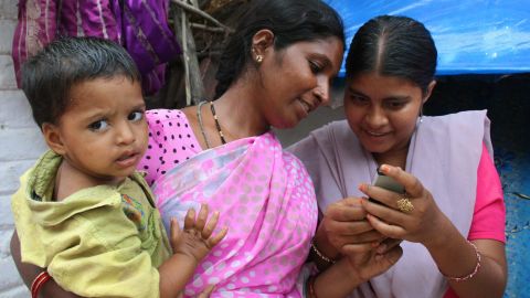Two women in India using a mobile-based reminder system for vaccinations.