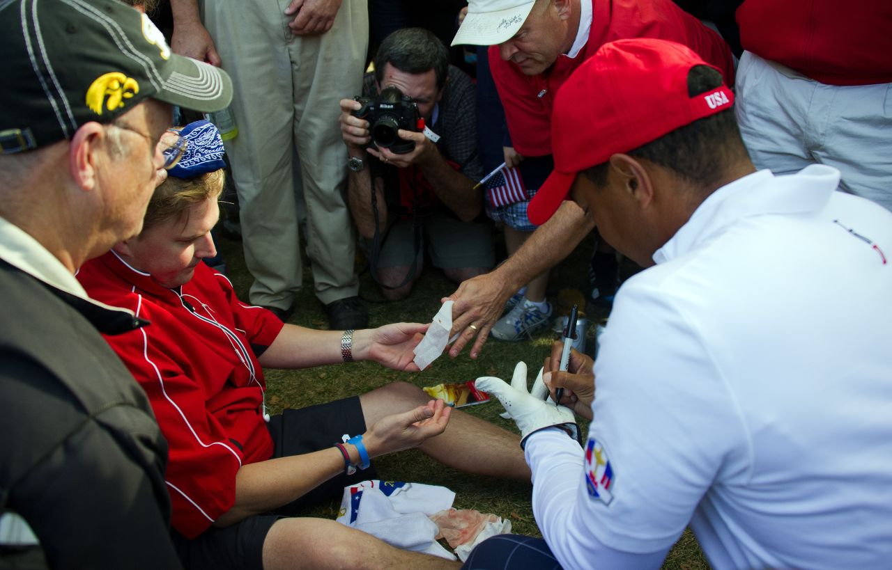 Tiger Woods signs his glove for a fan who was struck in the head during his drive off the seveth tee on Friday.