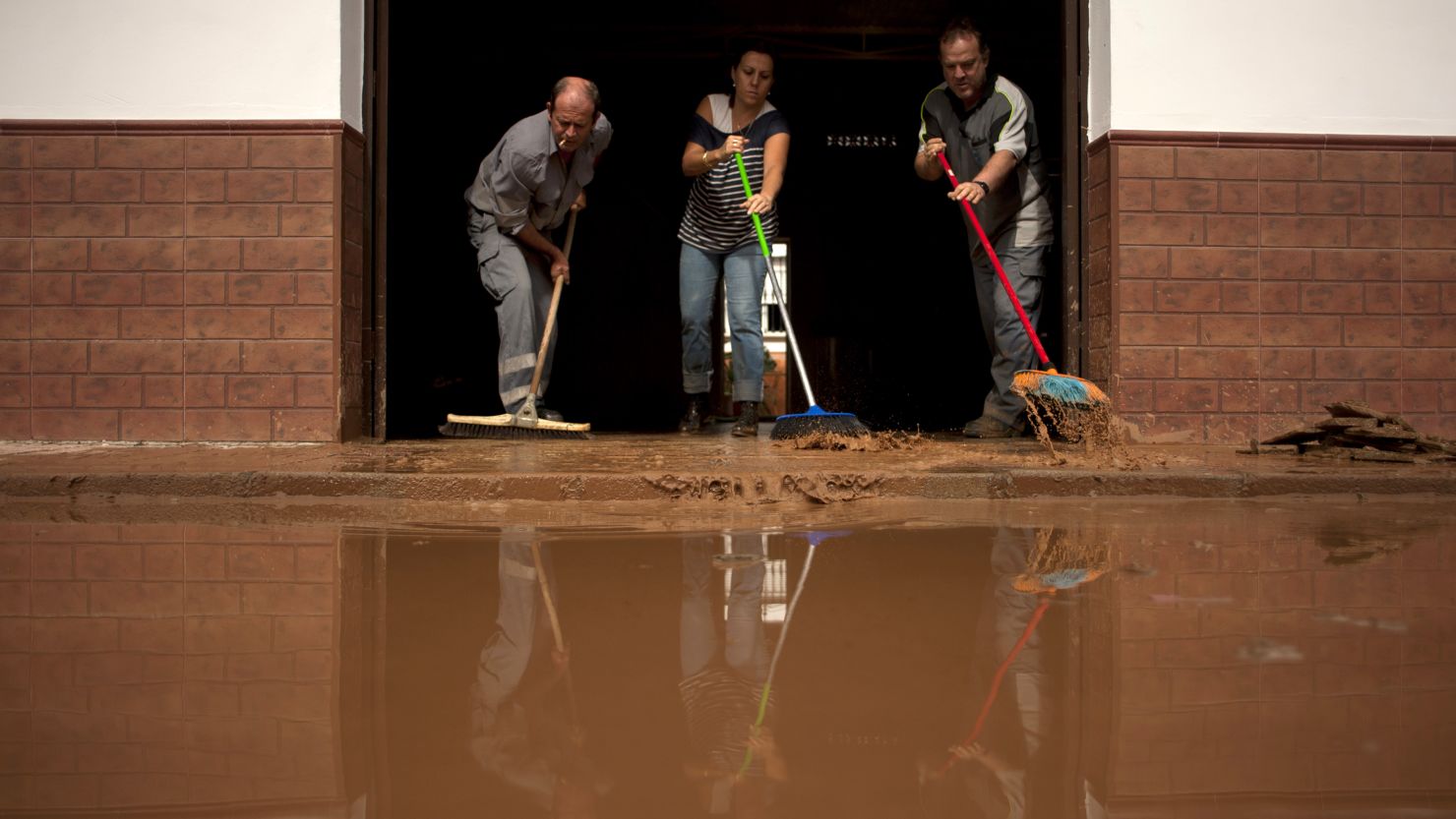 People clean the entrance of their flooded home in Bobadilla, near Malaga, southern Spain on September 29, 2012.