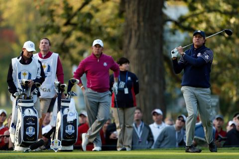 American Phil Mickelson watches his tee shot on the fourth hole as Lee Westwood of Europe looks on.