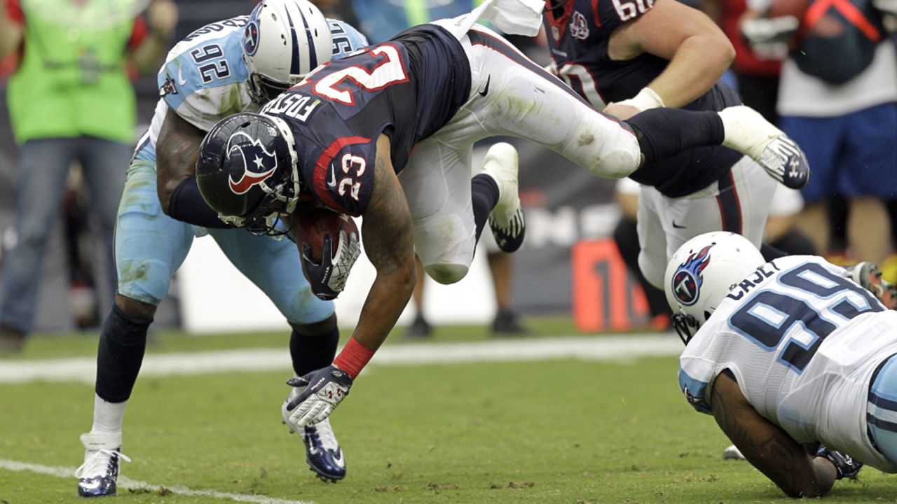 Arian Foster of the Houston Texans leaps over Jurrell Casey, No. 99 of the Tennessee Titans, as he is tackled by Will Witherspoon, No. 92, at Reliant Arena in Houston on Sunday.