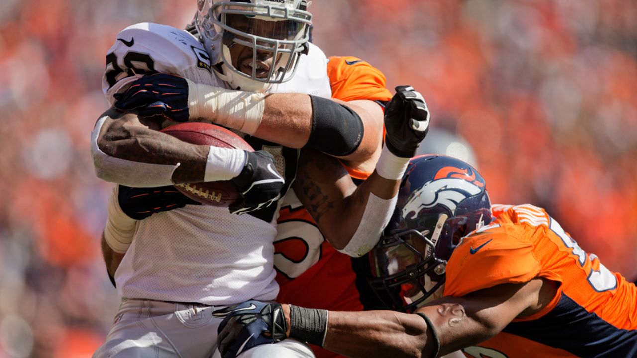 Darren McFadden of the Oakland Raiders is tackled for a loss by No. 95 Derek Wolfe and No. 52 Wesley Woodyard of the Denver Broncos on Sunday at Sports Authority Field Field at Mile High in Denver.