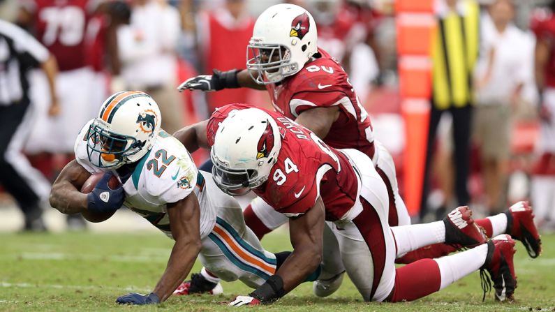 Reggie Bush of the Miami Dolphins is tackled in the backfield Sunday by No. 94 Sam Acho of the Arizona Cardinals.