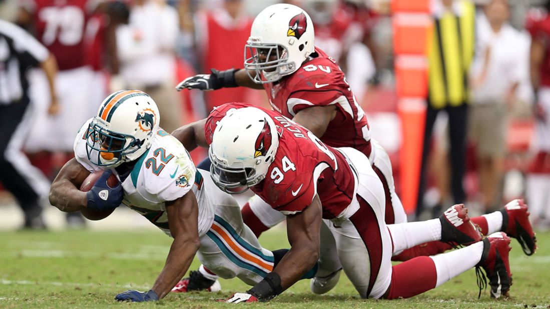 Reggie Bush of the Miami Dolphins is tackled in the backfield Sunday by No. 94 Sam Acho of the Arizona Cardinals.