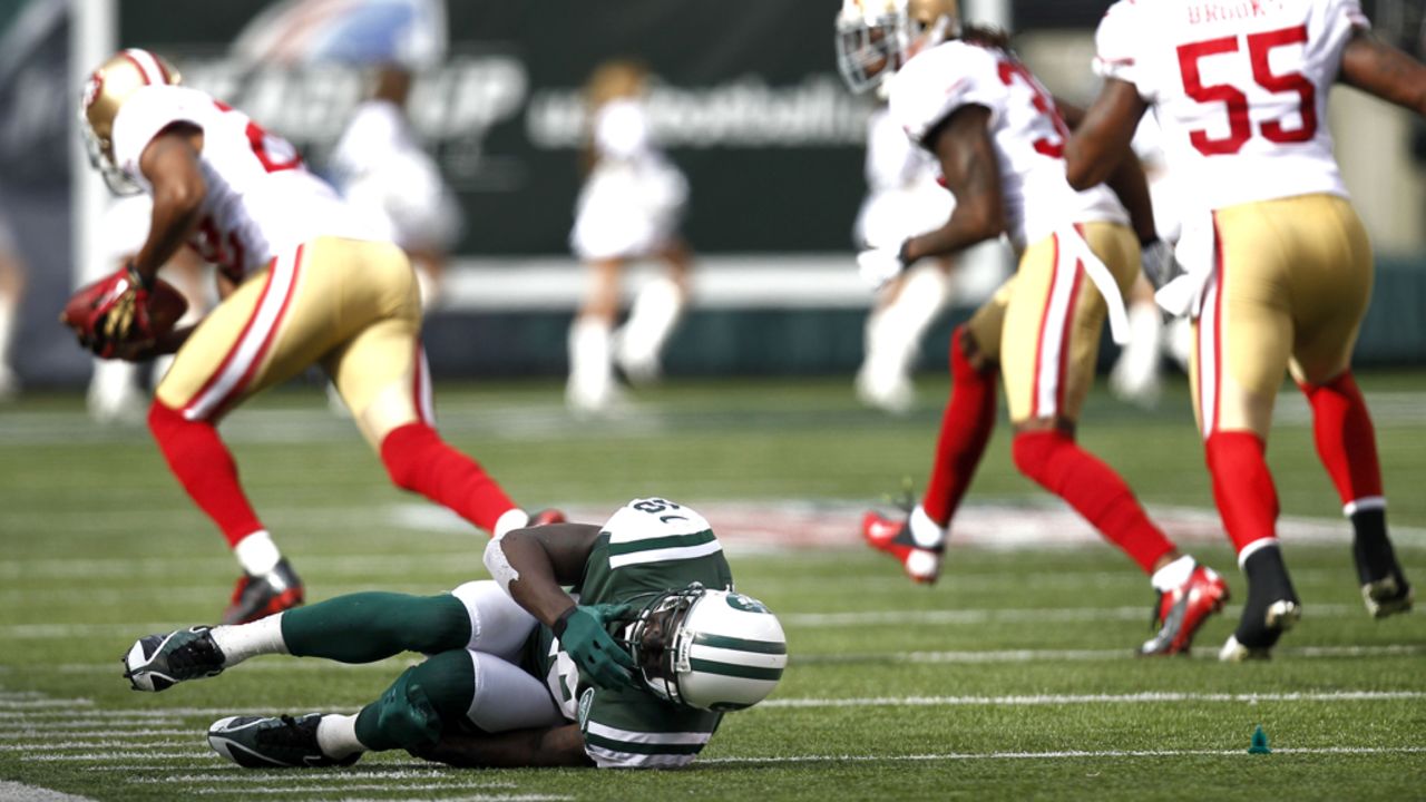 Santonio Holmes of the New York Jets writhes on the turf after fumbling a ball picked up by Carlos Rogers of the San Francisco 49ers on Sunday at MetLife Stadium in East Rutherford, New Jersey.