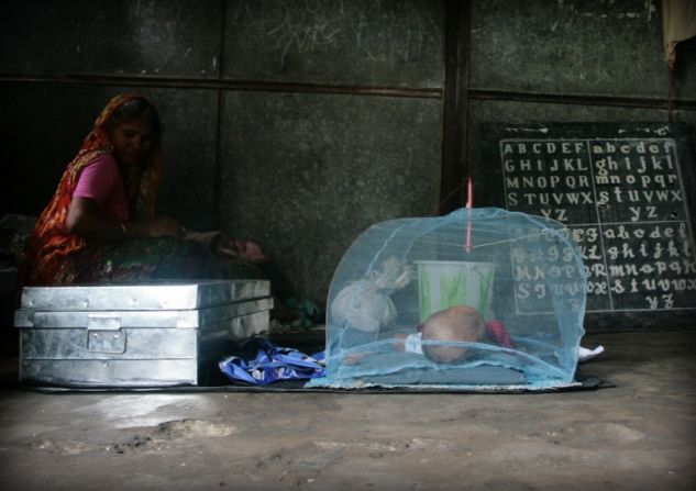 An infant sleeps in a classroom that has been converted into a dormitory.