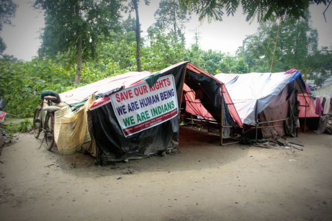 Relief camps set up in schools are overcrowded, and residents often need to set up makeshift tents on the surrounding grounds. In this Muslim camp, banners protest allegations that Muslim inhabitants in Assam are illegal immigrants from Bangladesh. 