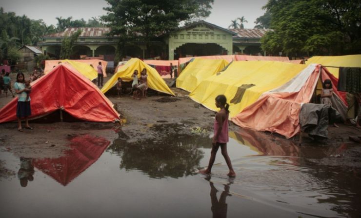 Prolonged monsoon rains in Assam flood the courtyards of schools being used as relief camps, forcing those who have taken refuge in tents to sleep many nights on the buildings' verandas and in hallways.
