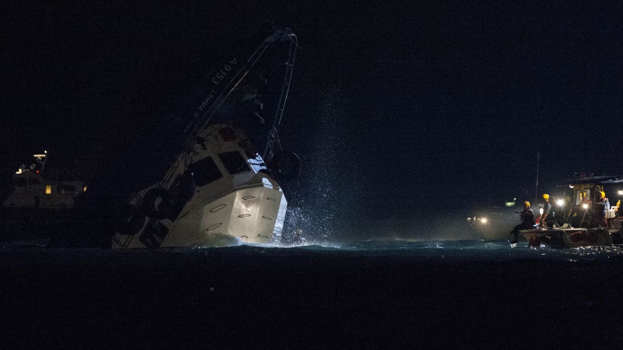 Rescuers approach the sinking vessel late Monday. 