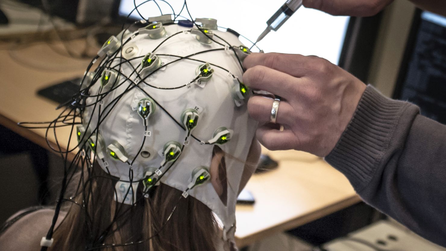A researcher makes an adjustment to a cap with electrodes at the Neuroscience Research Center in Lyon, France. 