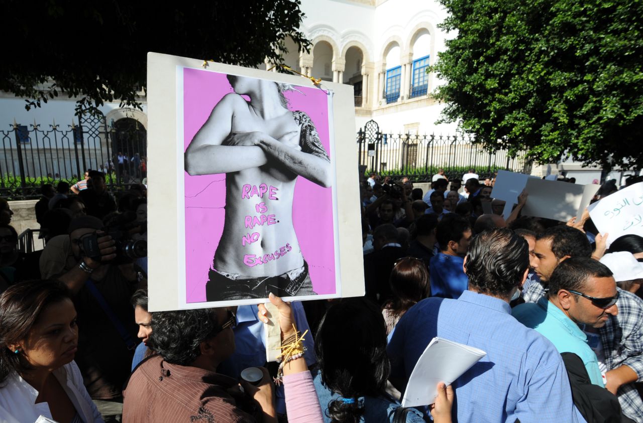 Tunisians hold signs Tuesday while protesting violence against women.