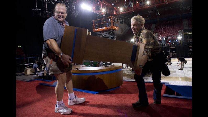 Workers carry a podium onto the stage on Monday.