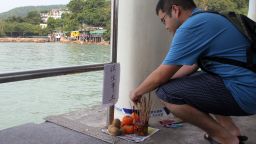 A man places incence sticks at a make shift offering on the Lamma Island pier off Hong Kong on October 3, 2012.