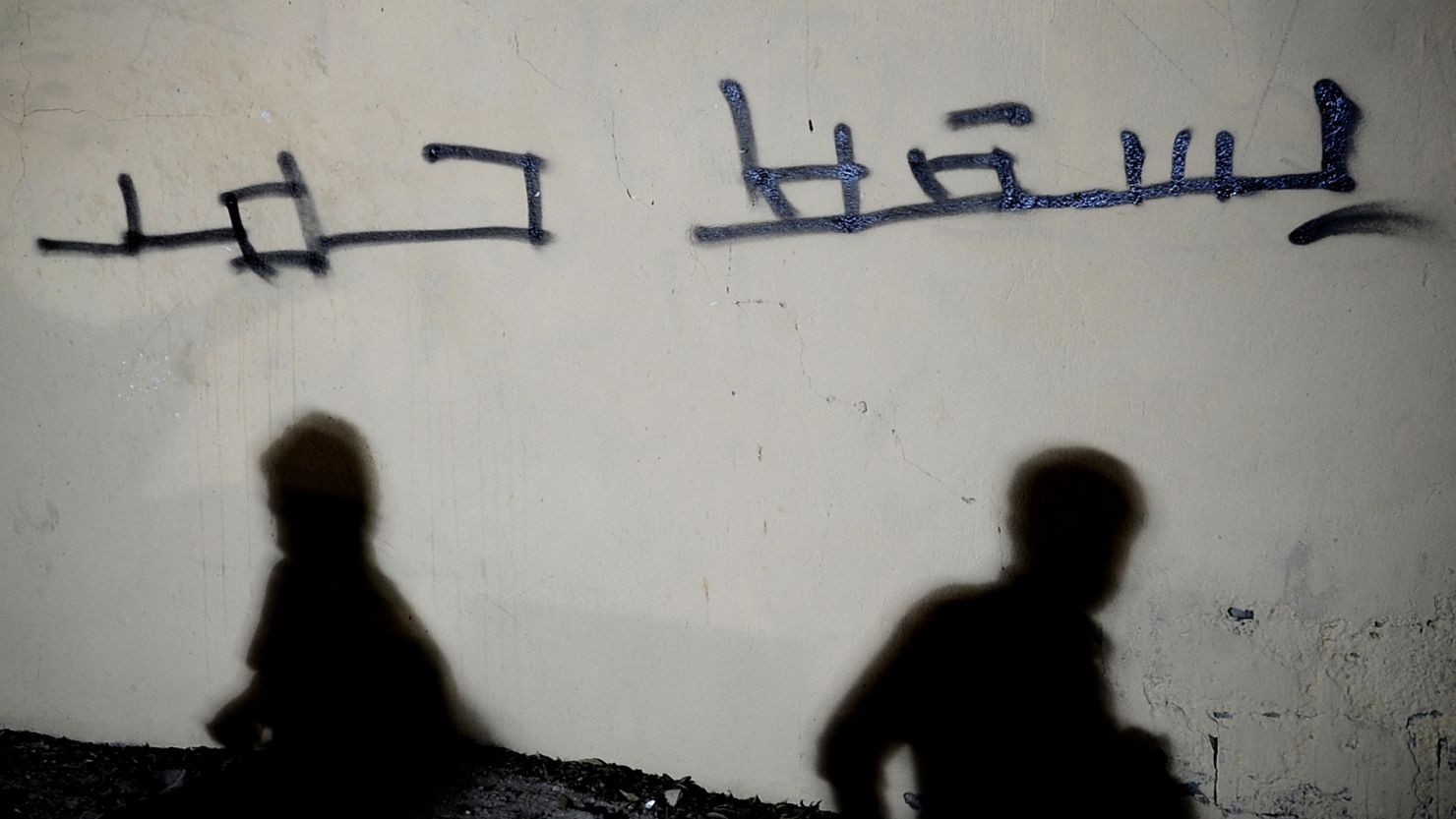 Shadows of Bahraini Shiites are seen on a wall with the Arabic writing "Down with Hamad" west of Manama on September 26. 