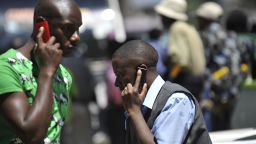 People walk while speaking on the phone on October 1,2012 in Nairobi, as Kenya confirmed a switch-off of counterfeit mobiles will take place at the end of the month.The mobile networks will be forbidden from activating new 'fake' devices bought after October 1. Government officials said the move was designed to protect consumers from hazardous materials and to safeguard mobile payment systems and prevention of crime. The government said three million users were using counterfeit handsets as of June. AFP PHOTO / SIMON MAINA (Photo credit should read SIMON MAINA/AFP/GettyImages) 