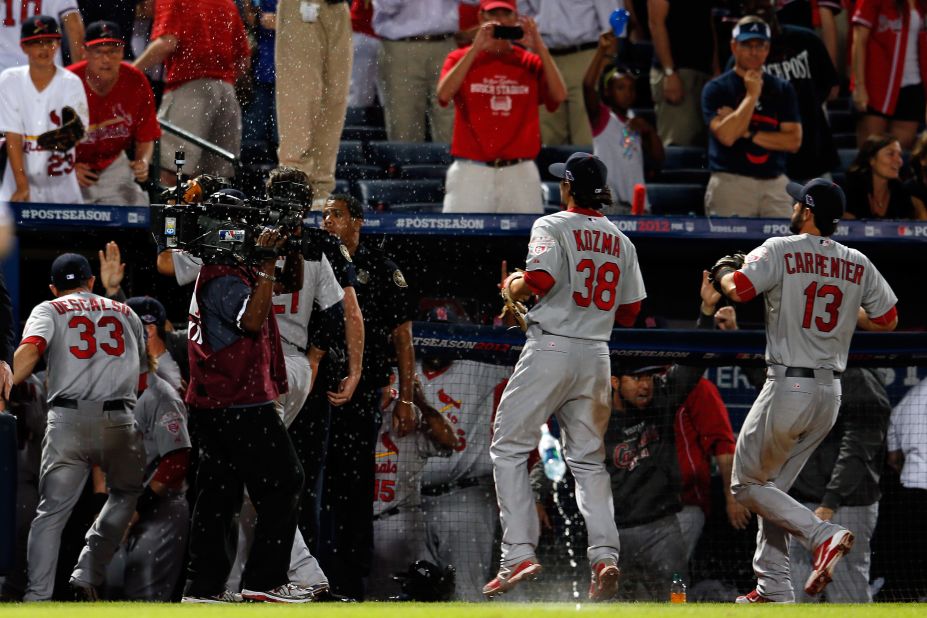 Cardinals Pete Kozma, left, and Matt Carpenter run into the dugout as debris rains onto the field.
