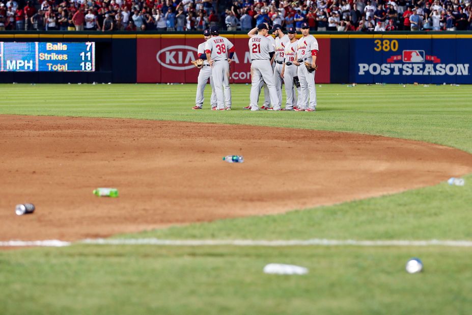 Cardinals players stand on the field as debris is removed.