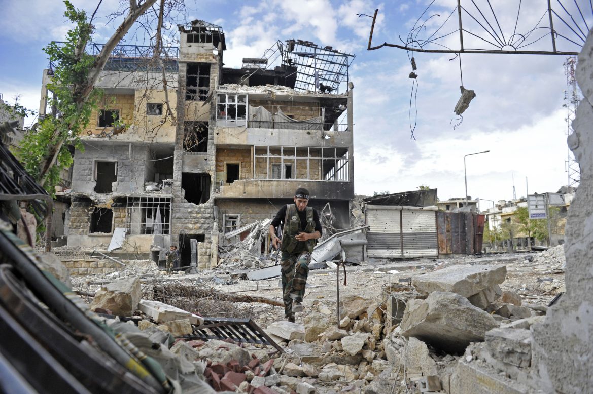 A Syrian rebel runs across a heavily damaged street to dodge sniper fire during clashes on Saturday.