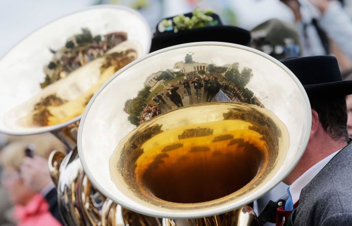 Visitors and the giant bronze sculpture 'Bavaria' are reflected in the brass players' instruments on Sunday.