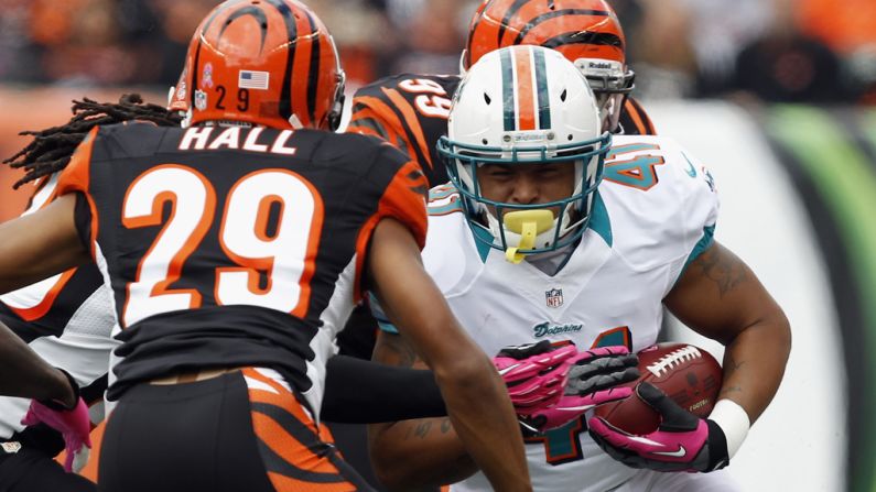 Jorvorskie Lane of the Dolphins tries to break tackles from Bengals defenders Leon Hall, No. 29, and Manny Lawson, No. 99.