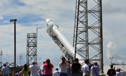 People watch as the SpaceX Falcon 9 rocket and its unmanned Dragon capsule are readied for launch Sunday in Cape Canaveral, Florida.