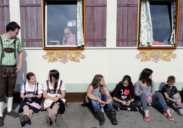 Young people, some dressed in traditional Bavarian clothing, wait outside a duck roast beer tent at the Oktoberfest beer festival in Munich, Germany, on Saturday, October 6.