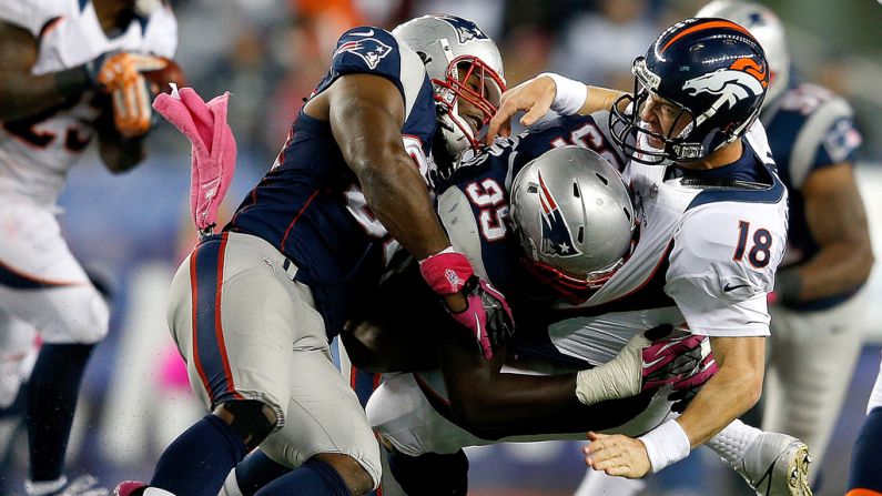 Jermaine Cunningham, left, and Chandler Jones of the New England Patriots rough up Peyton Manning of the Denver Broncos after he released a pass during the second half on Sunday.