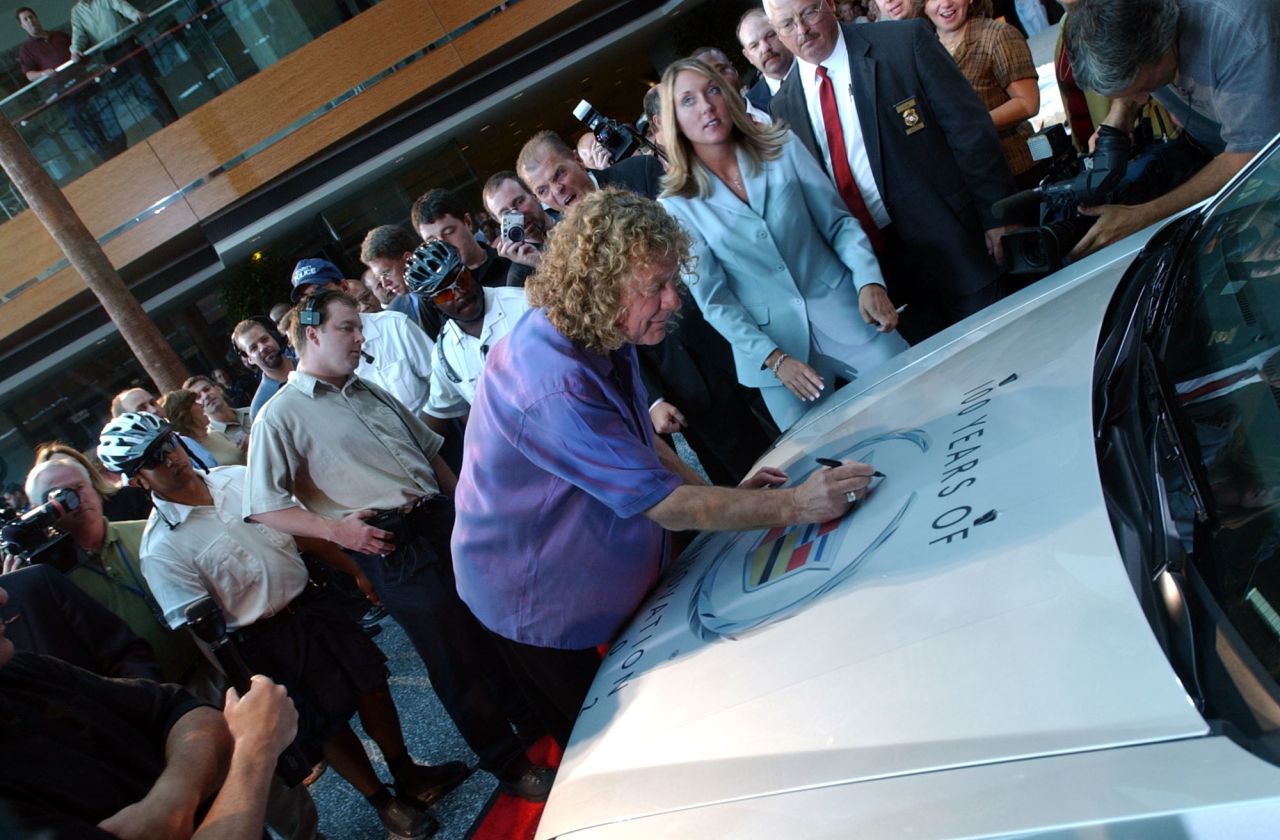 Lead singer Plant autographs the hood of a Cadillac CTS in Detroit in 2002. Led Zeppelin's music has been featured in Cadillac commercials.