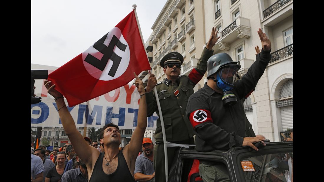 Demonstrators dressed as Nazis ride in an open-top car in Syntagma Square.