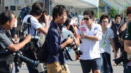 Sauber driver Kamui Kobayashi (white shirt) is the focus of constant media and public scrutiny as the 26-year-old walks in the paddock of  the Suzuka circuit on Saturday ahead of the Japanese Grand Prix. 