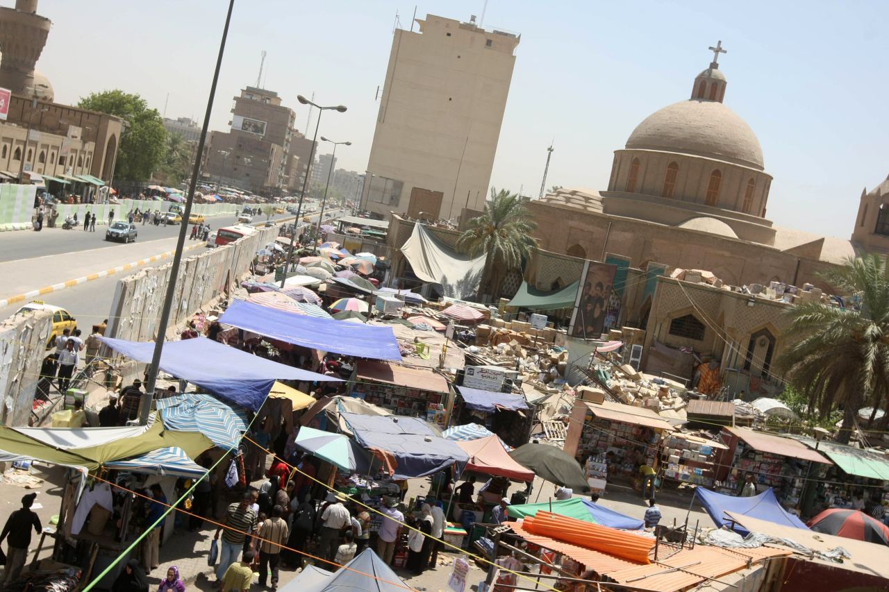 Markets in Baghdad (this one in 2010) are sometimes held in the shadows of blast walls in an effort to prevent suicide car bombings.