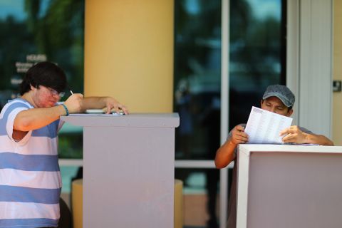 Allan Banojakedjian, left, and Jesus Romero fill out their voter registration forms at the Miami-Dade Elections Department on the final day of registration for the upcoming presidential election.