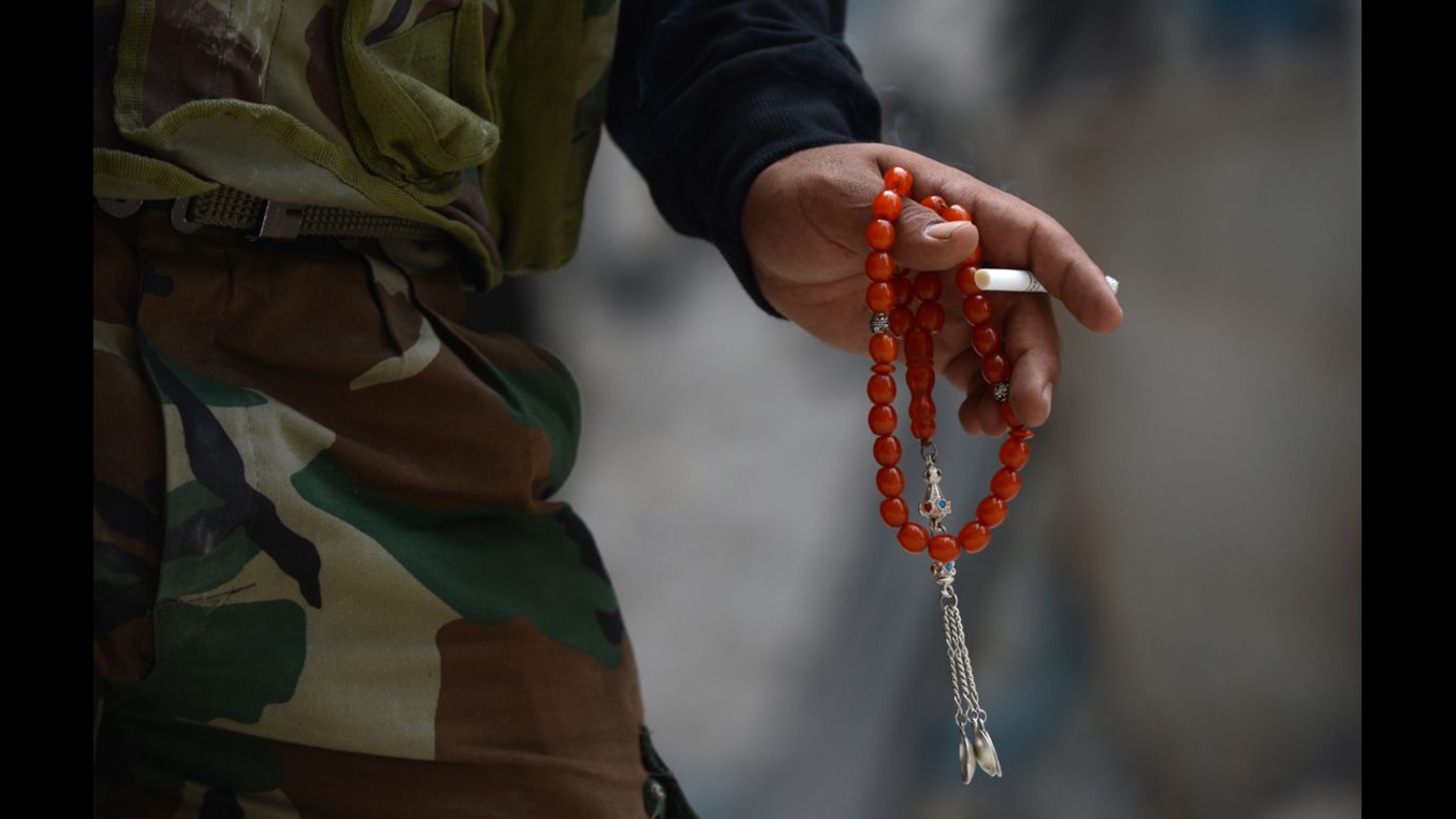 A Syrian rebel fighter holds a cigarette and prayer beads in Aleppo on Tuesday, October 9.