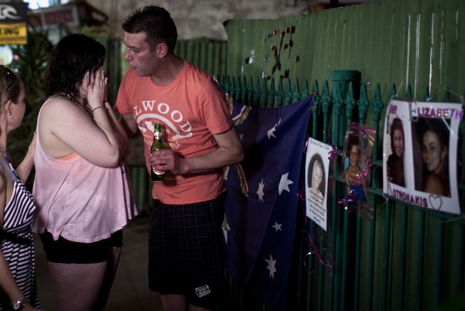 A grieving relative is comforted at the bomb site in Bali, October 10, 2012. Wreaths, flowers and photos are being left at the site as a temporary shrine to those killed. 