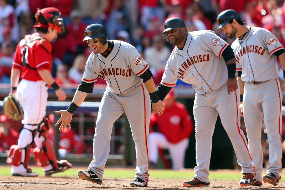 Teammates Marco Scutaro, Pablo Sandoval and Angel Pagan wait for Buster Posey at home plate after the Giants catcher hit a grand slam in the fifth inning off Cincinnati's Mat Latos.