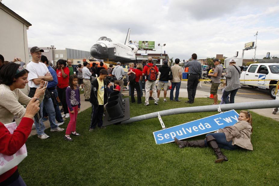 People pose with a street sign that was removed to make way for the space shuttle Endeavour during its transport from LAX to the California Science Center.