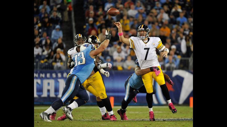 Roethlisberger, the Steelers quarterback, throws a pass while in a Titan's grasp.