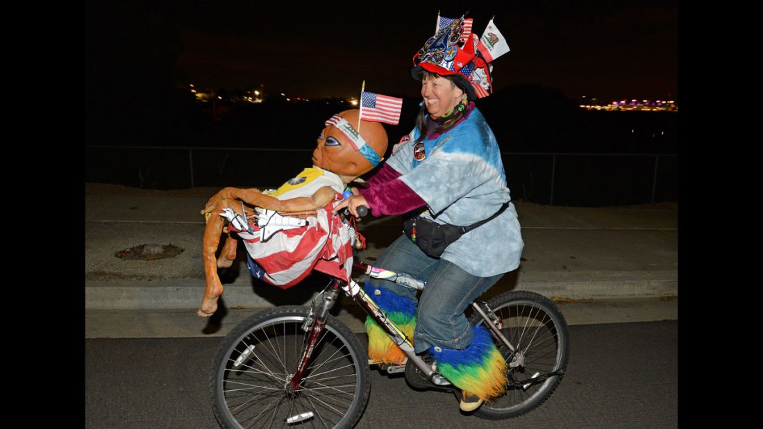 Fan Vivian Robinson rides her bicycle covered in shuttle memorabilia, American flags and an alien doll outside the Los Angeles airport as she waits to see Endeavour.