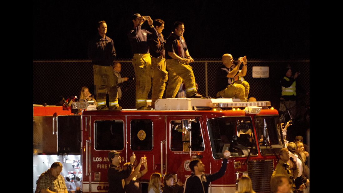 Firefighters and other spectators document the move early Friday. 