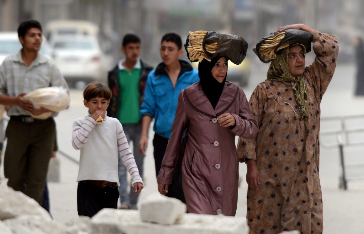 Syrian people carry bread as they walk in the streets of Aleppo on Thursday.