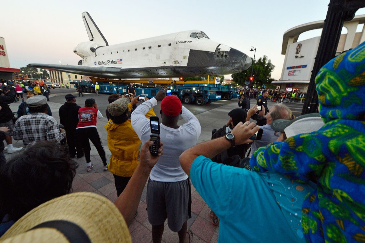 Crowds look on as Endeavour is transported to The Forum arena before sunrise on Saturday.
