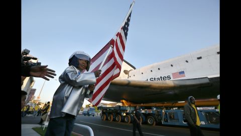 Amir Morris, 3, holds an American flag as the shuttle passes by in Inglewood on Saturday.